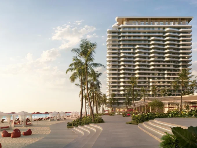 Rosso Bay Residences, a tall building on a sunny beach with palm trees and cabanas.